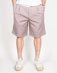 Uomo in Bermuda Fresco, modello di pantaloni corti, colore chiaro, indossati con scarpe sportive.