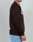 Side view of a man wearing a brown Felpa Superculture Girocollo Cortina Ski Club sweatshirt.