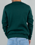 Back view of a man wearing Felpa Superculture Girocollo St. Moritz, green sweatshirt, styled with light blue jeans.