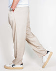 Uomo che indossa pantalaccio misto lino, in tessuto leggero, colore beige, con scarpe sportive.