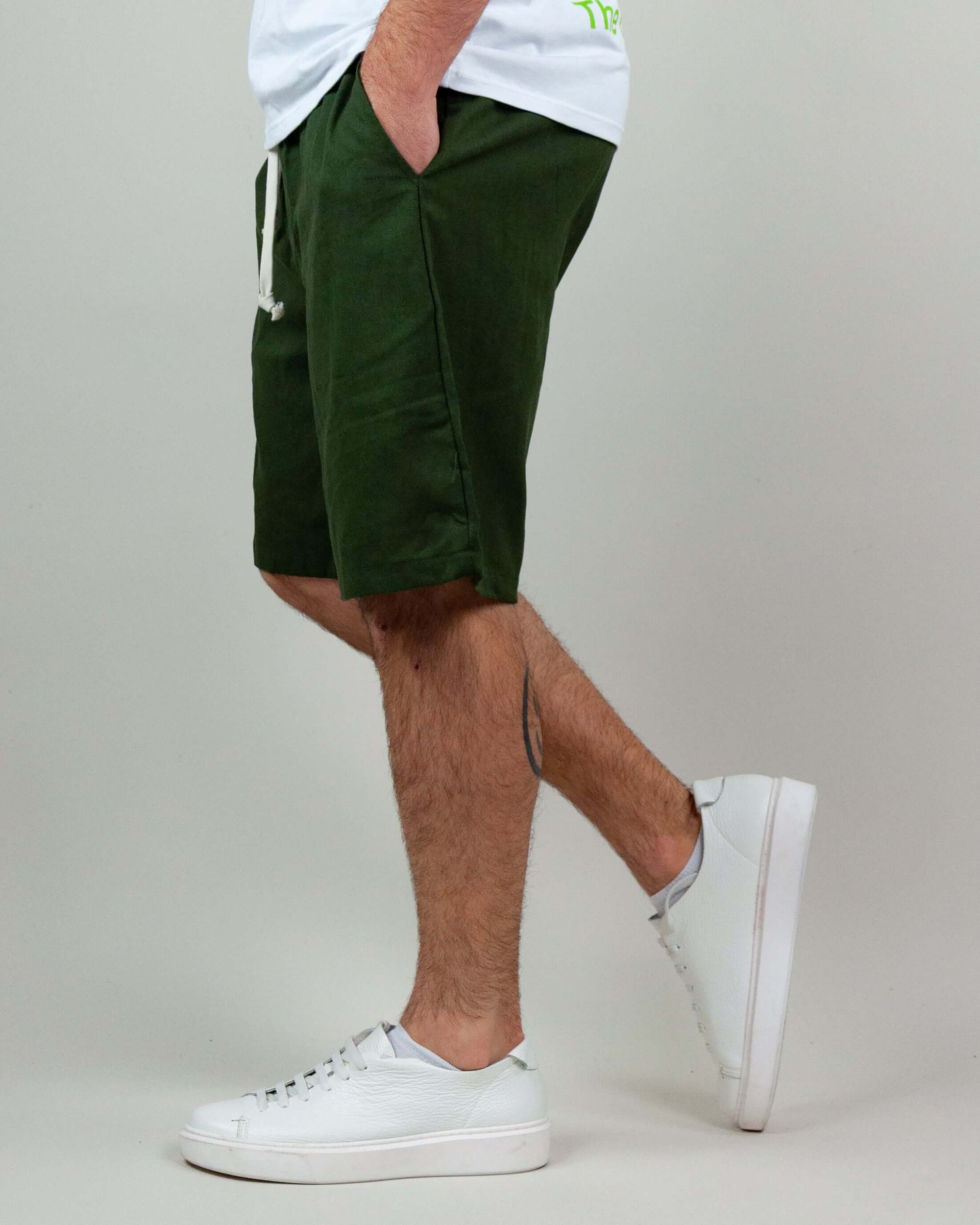 Men's green Bermuda shorts styled with a white t-shirt and white sneakers, showcasing a casual summer look.