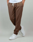 Comfortable brown linen-rayon blend pants for men, styled with a drawstring and white sneakers.