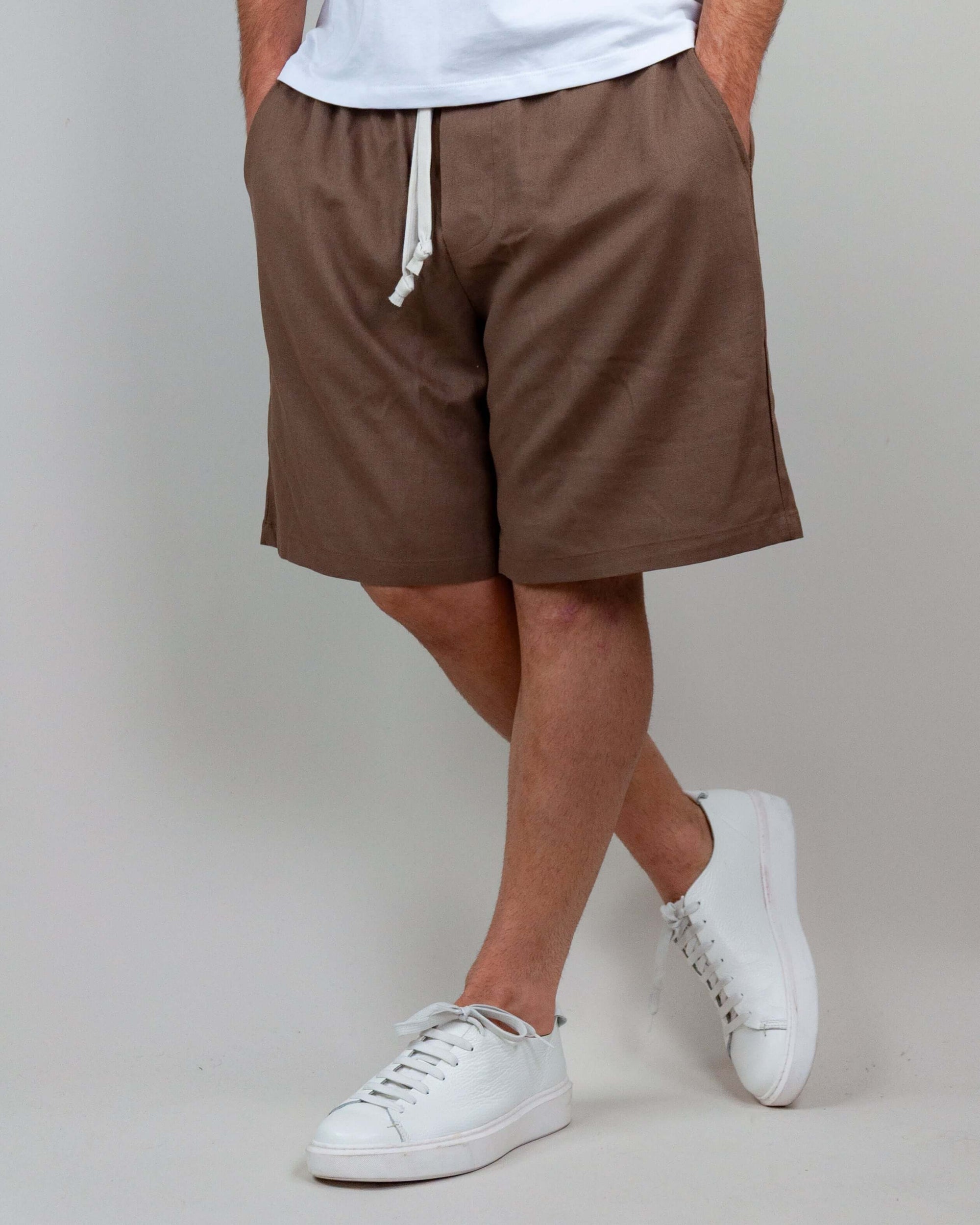 Bermuda shorts in brown, made of linen and rayon, styled with a casual white t-shirt and sneakers.