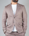 Model wearing Completo Lino Officina36 fango suit jacket over a white shirt, showcasing sophisticated linen fabric.