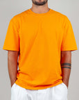 Model wearing an orange t-shirt, semi-over fit, made of 100% cotton, perfect for casual outfits.