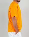 Side view of a man wearing an orange semi-over T-shirt made of 100% cotton.