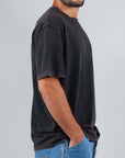 Man wearing a micro logo Amish art T-shirt in black, featuring a semi-overfit silhouette and 100% cotton fabric.