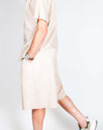 Uomo in completo popeline beige elegante, giacca e pantaloni corti per look estivo sofisticato.