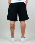 Back view of bermuda shorts, showcasing a relaxed fit and a smiley tattoo on the leg.
