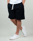 Bermuda shorts in black fabric with drawstring, styled with white sneakers for a casual summer look.
