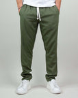 Pantaloni misto lino e rayon, colore verde, con tasche e coulisse, abbinati a sneakers bianche.