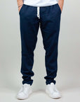Uomo indossa pantaloni blu scuro in misto lino e rayon con sneakers bianche, perfetti per comfort e stile.