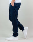 Side view of navy blue Pantalaccio Paros, made from linen and rayon, paired with white sneakers.