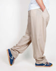 Pantalone con pince fondo ampio in misto lino, modello aderente con tasche, indossato da un uomo con scarpe sportive.