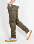 Uomo in pantalone slim fit cotone color oliva, indossato con scarpe bianche e blu.