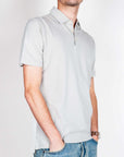 Uomo che indossa una polo manica corta in cotone grigio chiaro, stile casual.