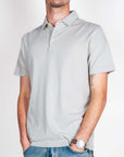 Polo manica corta in cotone grigio indossata da uomo in taglia L, con orologio e jeans.