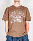 Model wearing a brown t-shirt Amish with Face Ghost University graphic, size M, 100% cotton.