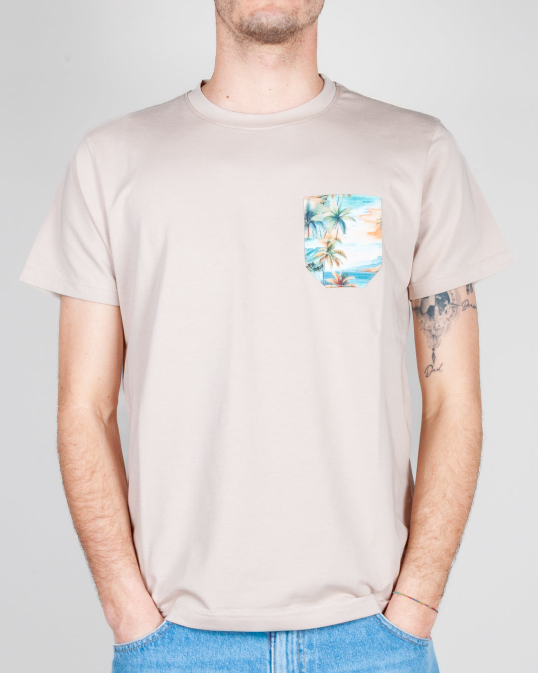 Uomo che indossa un T-shirt taschino V2 Art. TUCL, colore beige con taschino a motivi floreali.