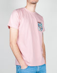 Un giovane indossa un T-shirt taschino V2 Art. TUCL con una tasca decorativa e una tonalità rosa.