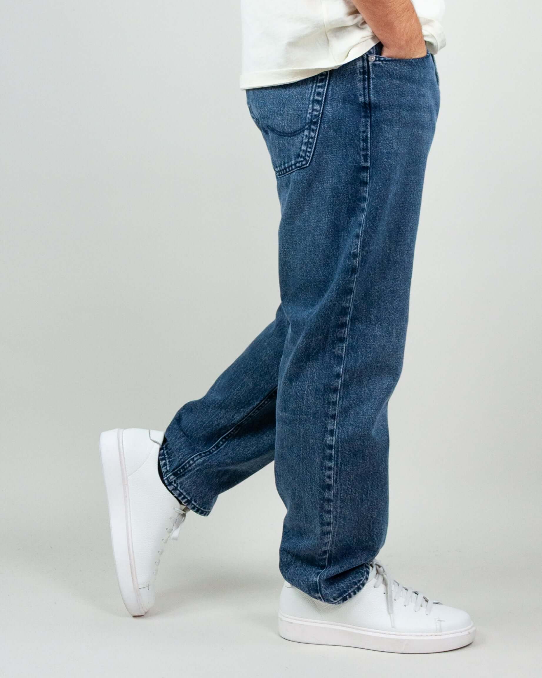 Man wearing Jack&Jones Eddie Baggy Jeans, size 31, in blue denim, paired with stylish white sneakers.