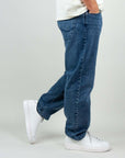 Man wearing Jack&Jones Eddie Baggy Jeans, size 31, in blue denim, paired with stylish white sneakers.