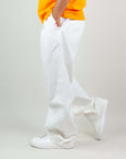 Side view of a man wearing white twill pants with pockets, paired with a bright yellow t-shirt and white sneakers.