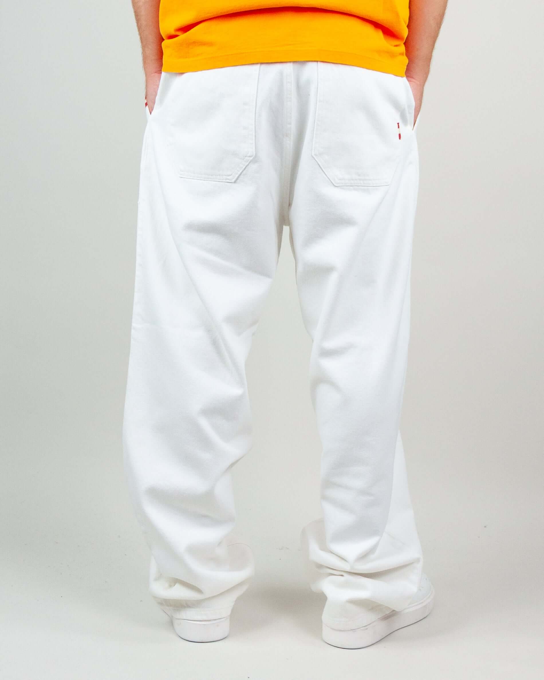 Rear view of white twill pants on model wearing an orange shirt, showcasing a casual style.
