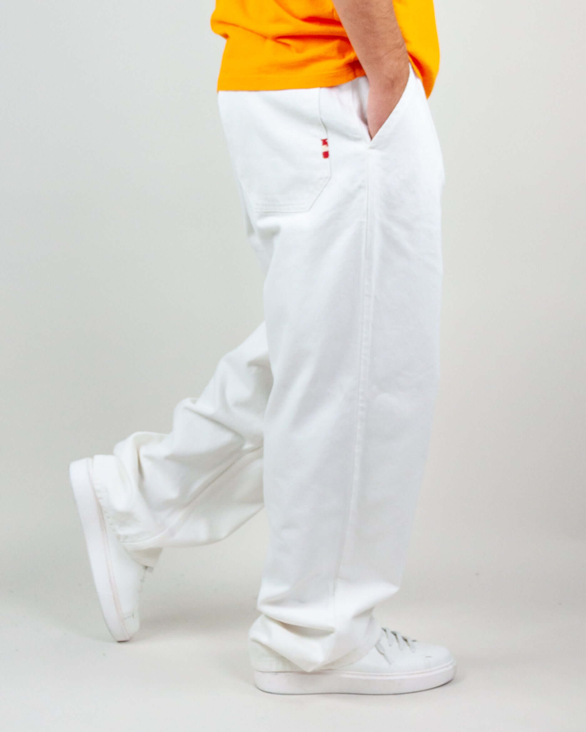 Pantalone Twill Amish Nogend Art in white, model wearing size M, 100% cotton, styled with a bright orange shirt.