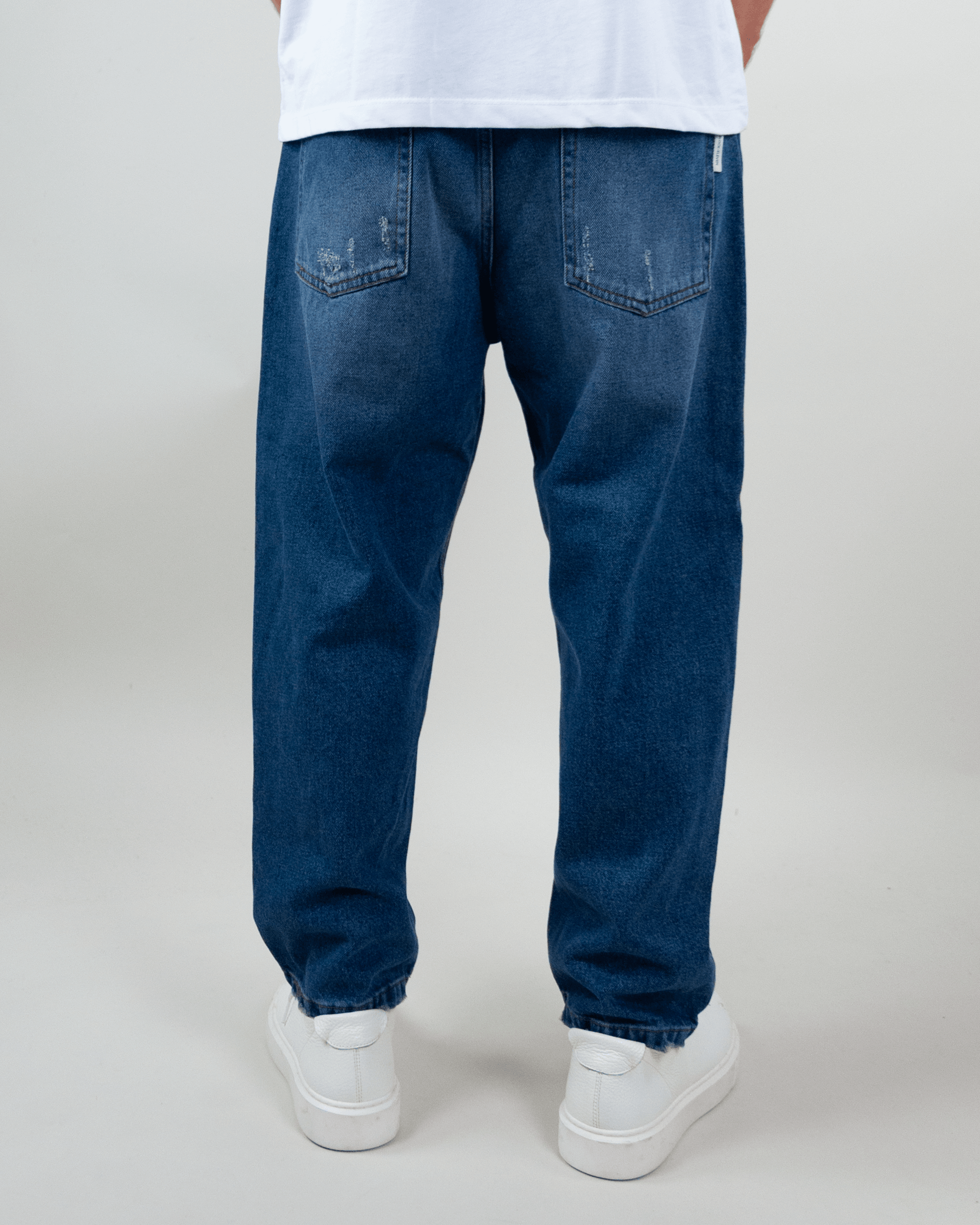 Back view of Jeans Coulisse Uomo in blue, featuring a relaxed fit and cuffed hems.
