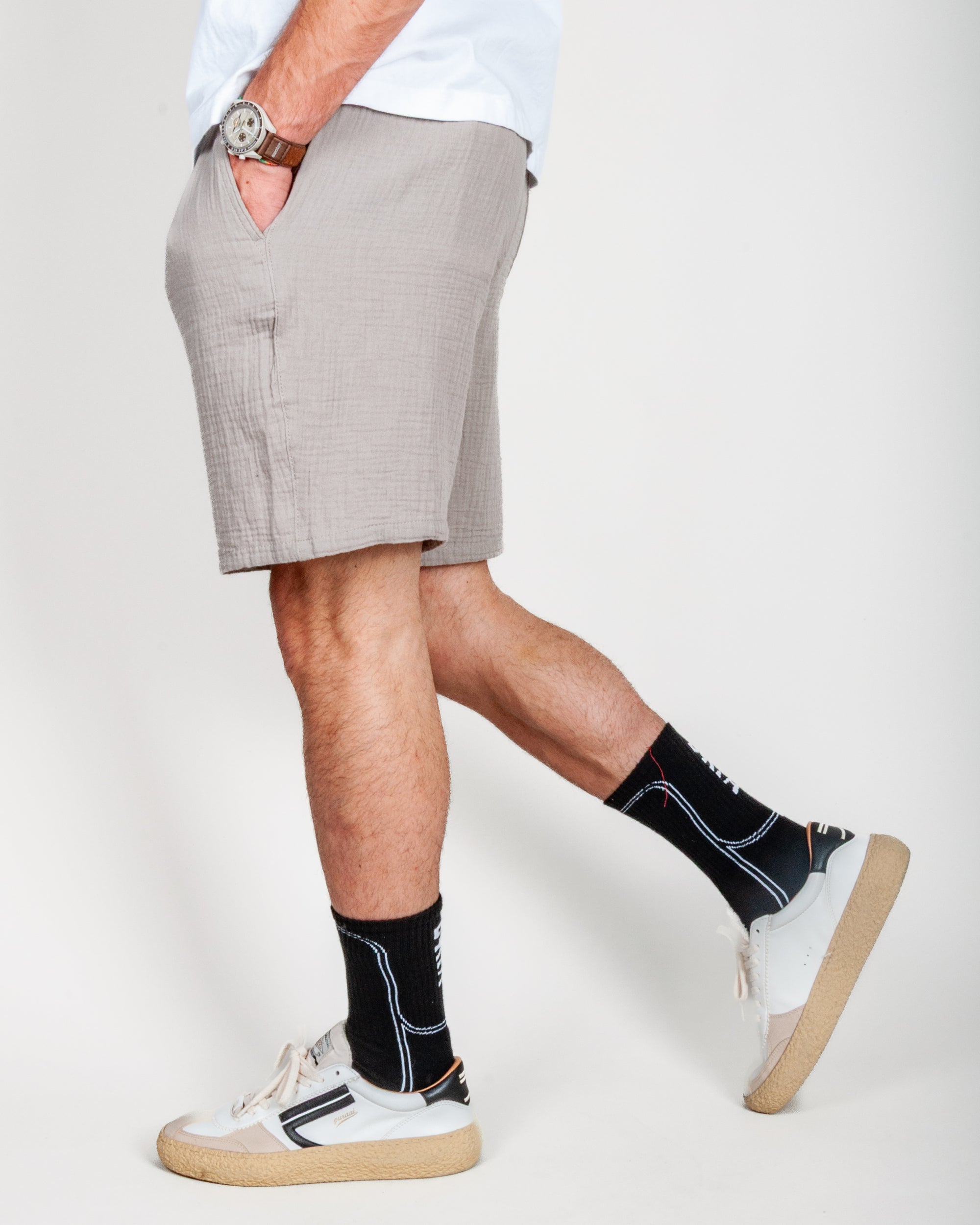 Uomo in Bermuda goffrato beige con calze nere e scarpe bianche, taglia L, in cotone organico.