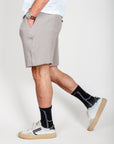 Uomo in Bermuda goffrato beige con calze nere e scarpe bianche, taglia L, in cotone organico.