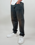 Amish Jeremiah Green dirty denim jeans displayed on a model wearing white sneakers, showcasing stylish casual wear.