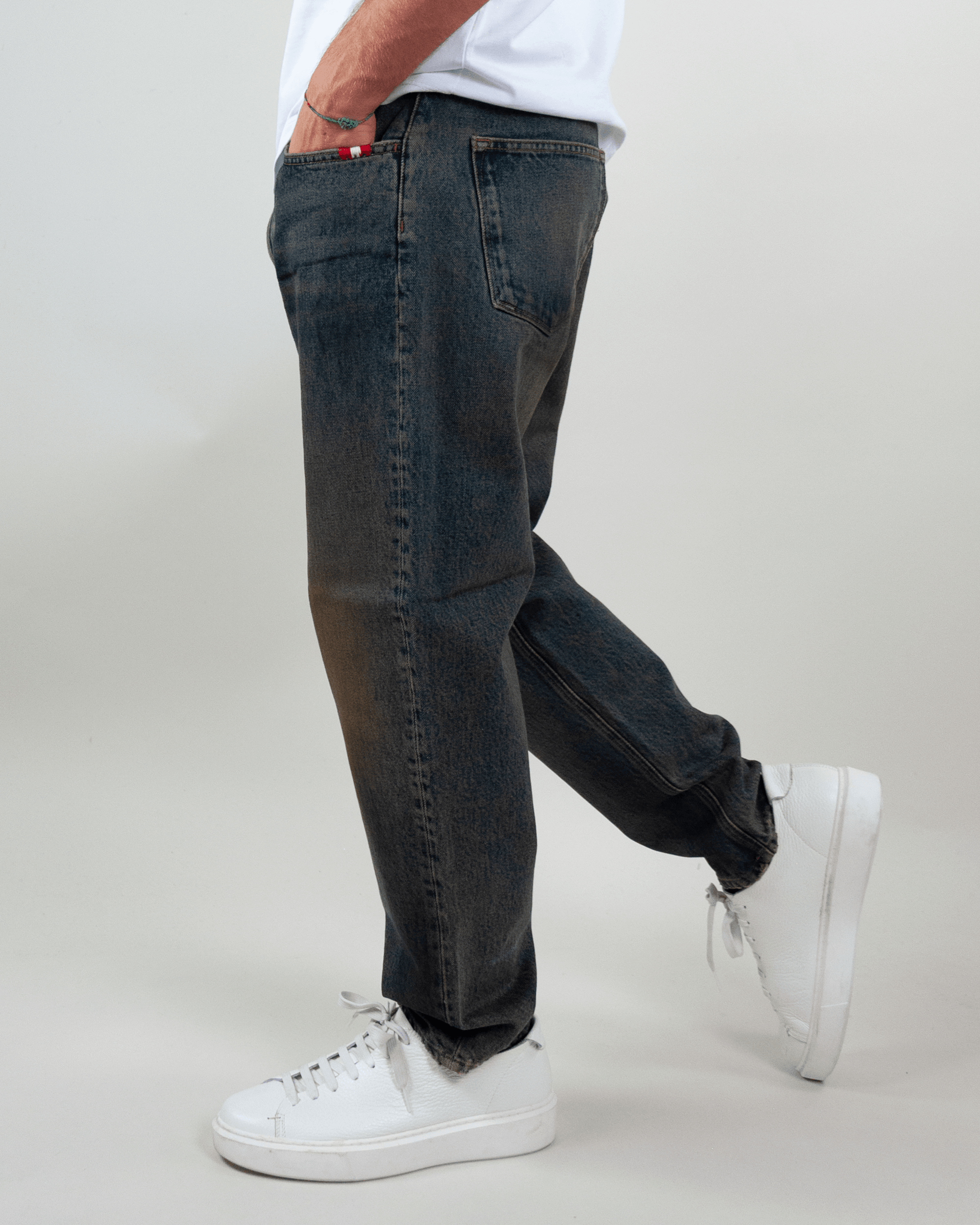 Amish Jeremiah Green dirty denim jeans worn by a person, showcasing a stylish side view with sneakers.
