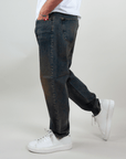 Amish Jeremiah Green dirty denim jeans worn by a person, showcasing a stylish side view with sneakers.