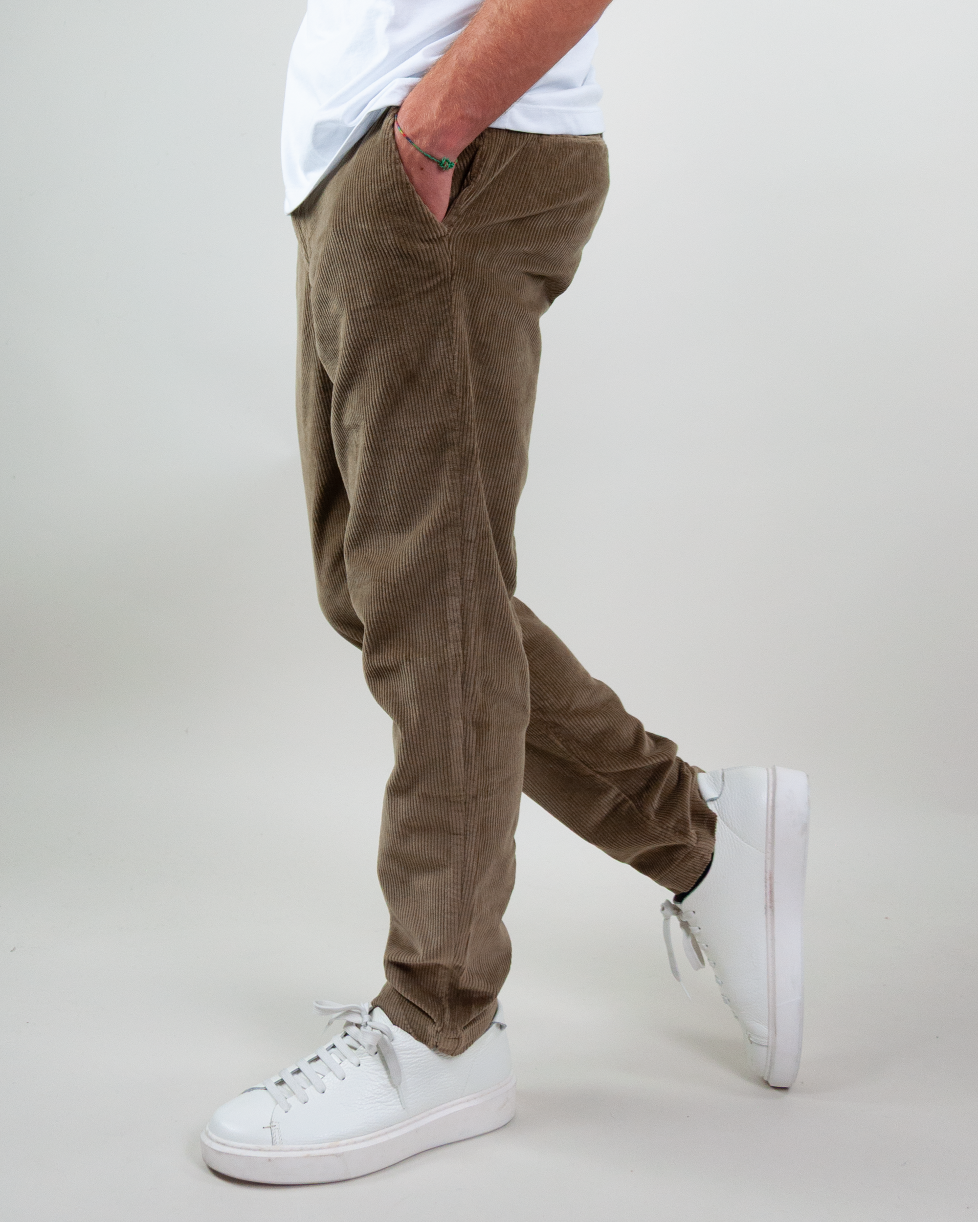 Side view of a man wearing Jack & Jones pantalone velluto in brown with white sneakers.