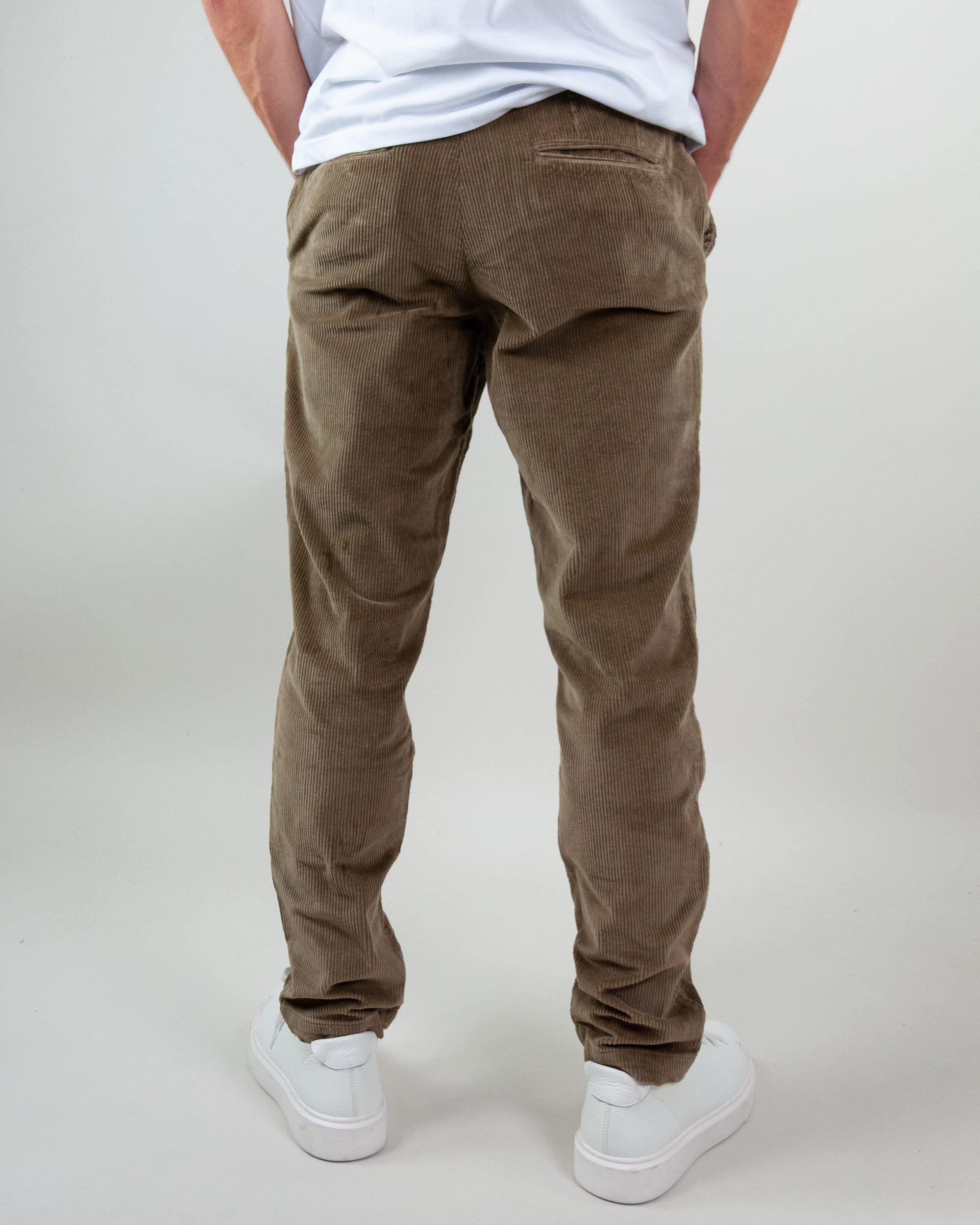 Back view of Jack & Jones pantalone velluto, model wearing brown corduroy pants with white shoes.