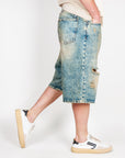 Bermuda Ampio in Denim I'm Brian worn by model, showcasing the distressed denim style, paired with white sneakers.