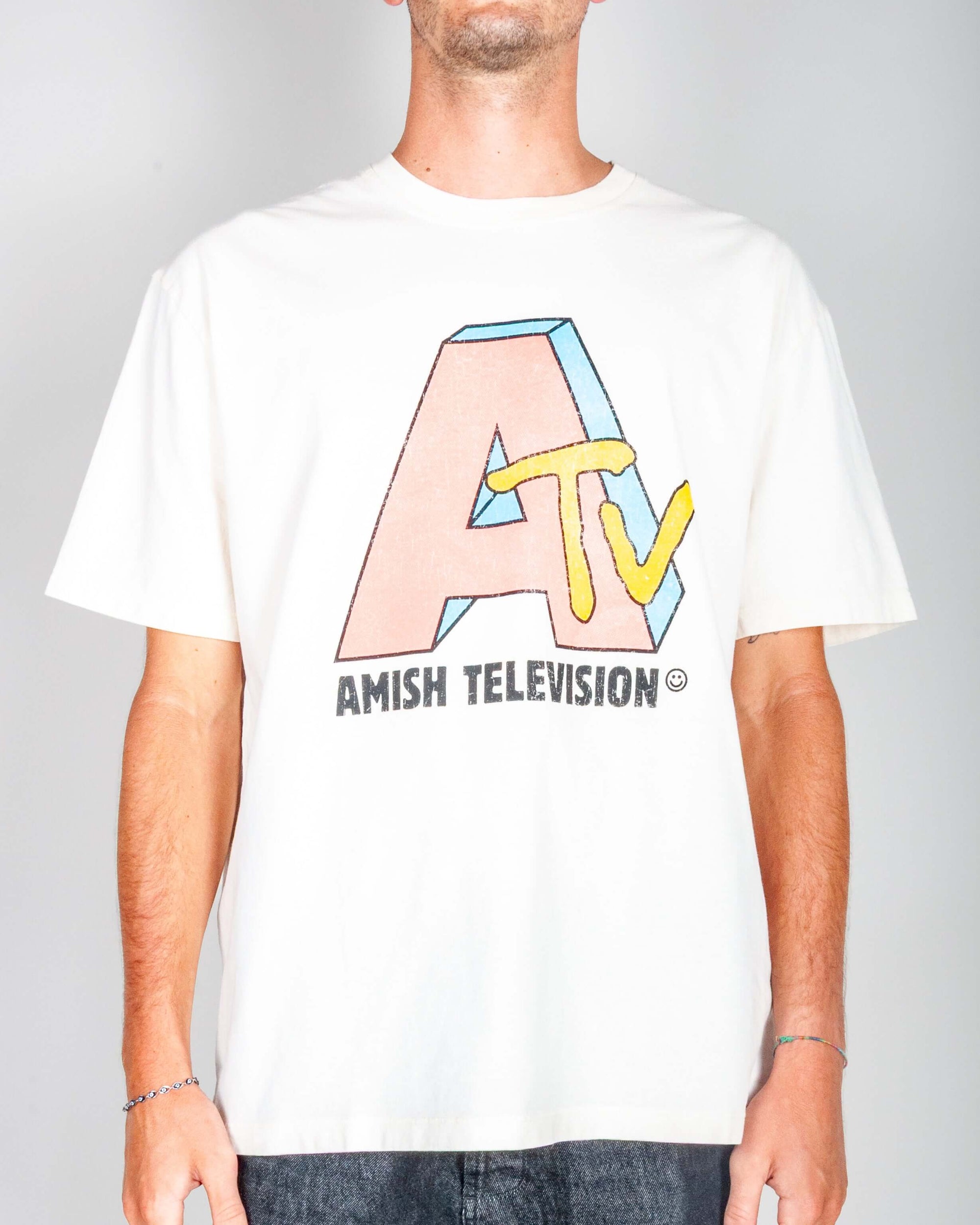 T-shirt artigianale Amish in cotone panna con stampa 'AMISH TELEVISION', modello indossa taglia M.