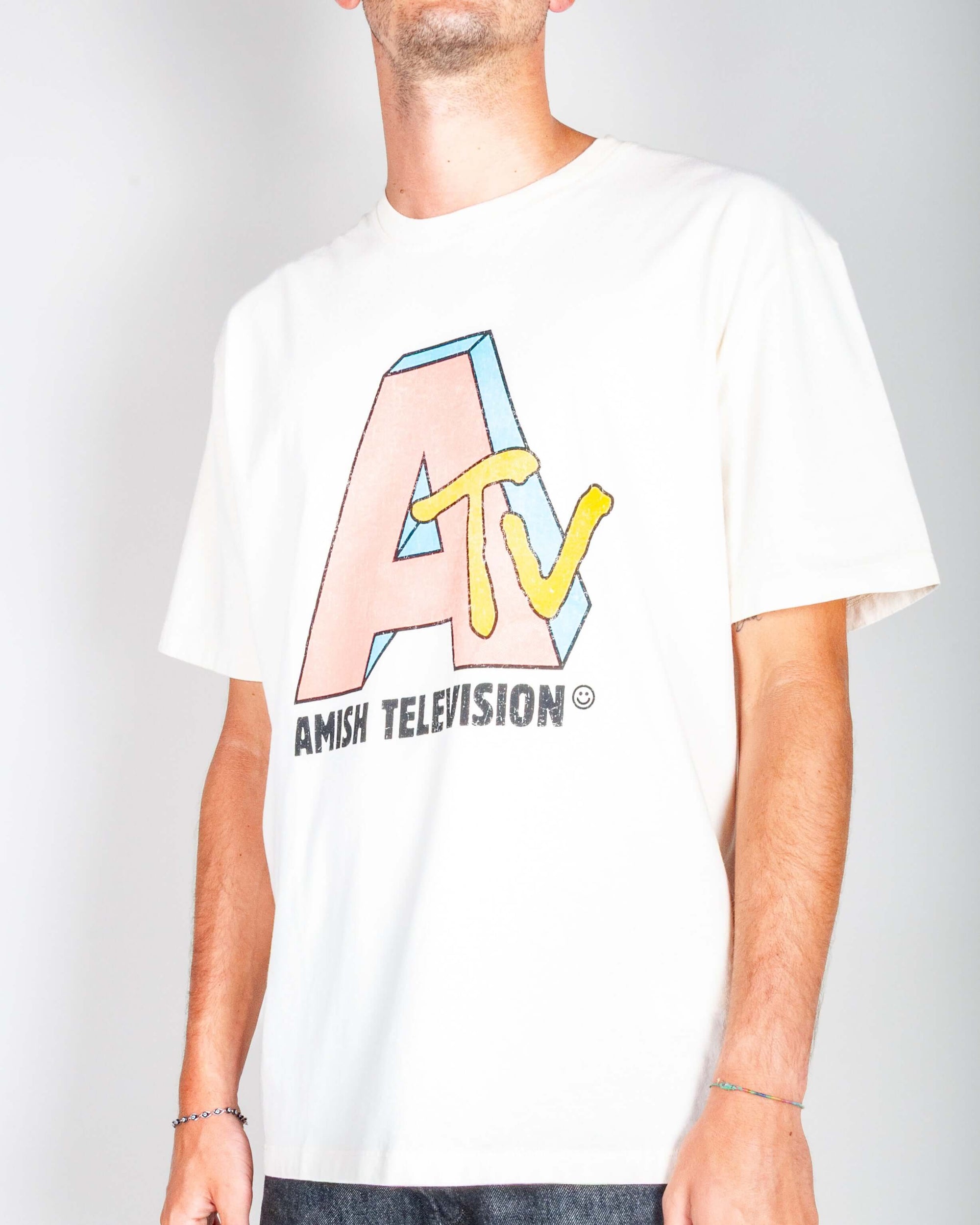 T-shirt artigianale Amish indossata da un modello, con logo colorato 'Amish Television'.