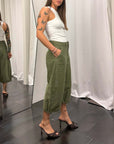 Bermuda lungo da lavoro donna in tessuto verde, modello elegante abbinato a top bianco e scarpe con tacco.