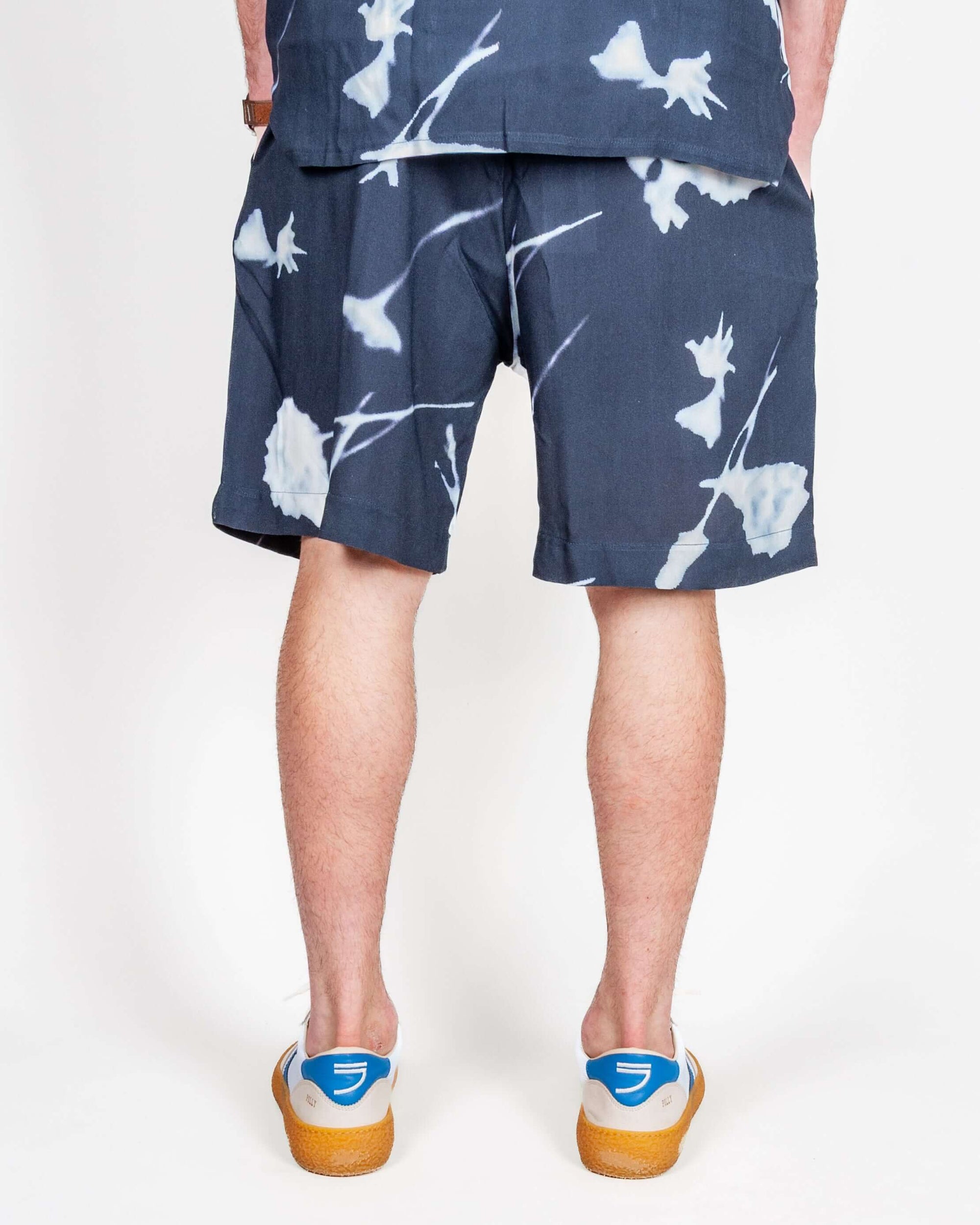 Bermuda Viscosa Why Not Brand Art model wearing dark floral shorts from the back view, showcasing the fabric design.