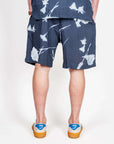 Bermuda Viscosa Why Not Brand Art model wearing dark floral shorts from the back view, showcasing the fabric design.