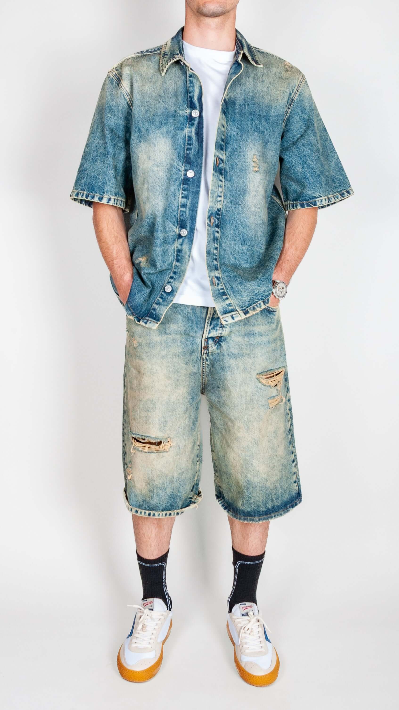 Completo in denim showcased by a model wearing a distressed denim shirt and shorts.