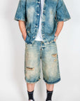 Completo in denim showcased by a model wearing a distressed denim shirt and shorts.