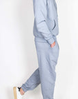 Completo Felpa Superculture grigio worn by a model standing side view, featuring a grey hoodie and jogger pants.
