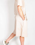 Completo popeline beige elegante indossato da uomo, composto da camicia e pantaloni, abbinato a sneakers alla moda.