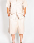Completo popeline beige elegante indossato da uomo, composto da camicia e pantaloni corti, look casual e elegante.