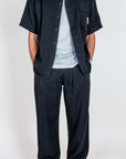 Completo in Lyocell Double Label Nero displayed on a model in a black shirt and pants paired with a light t-shirt.