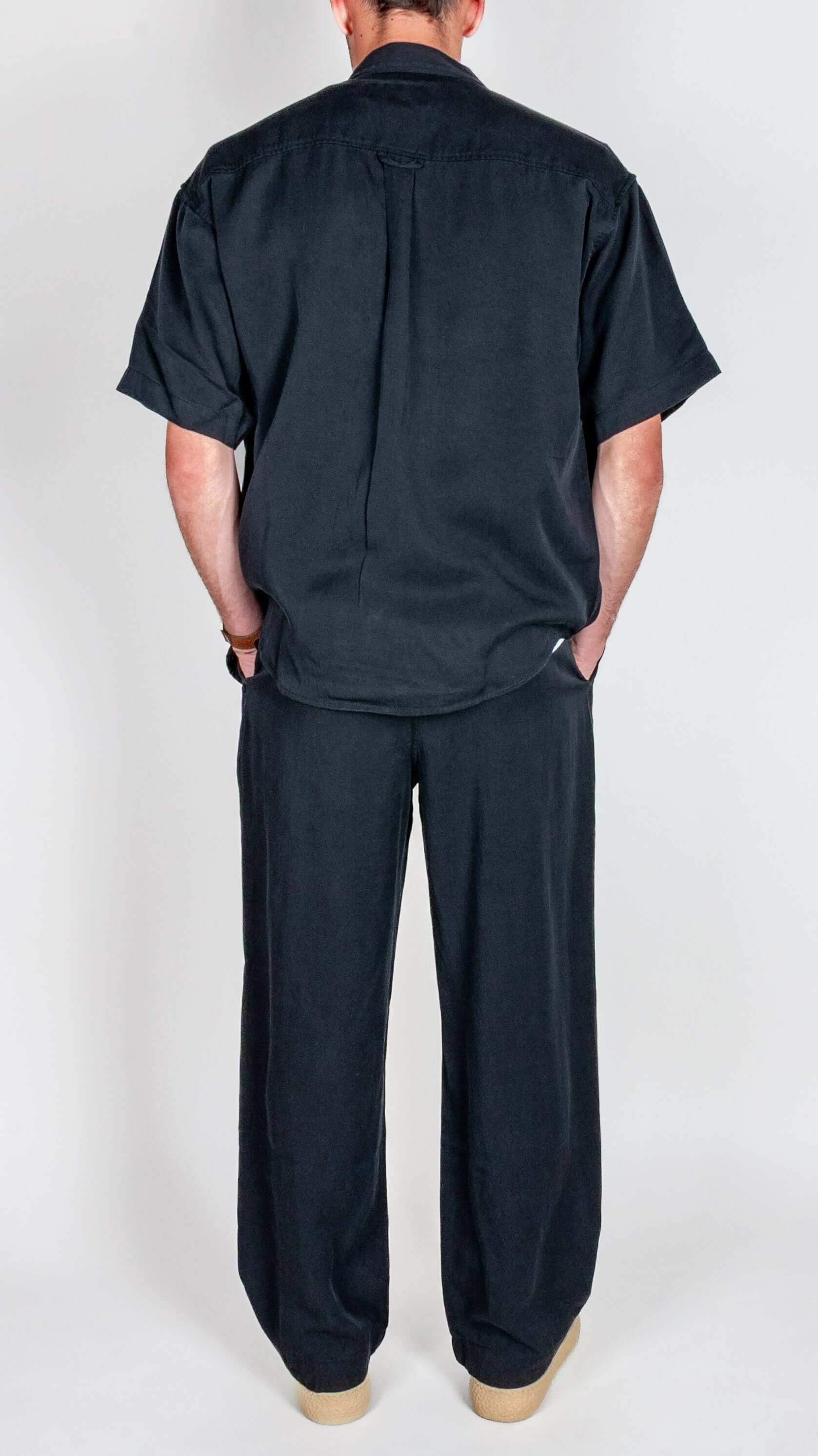 Completo in Lyocell Double Label Nero shown from the back, featuring a stylish black shirt and pants outfit.
